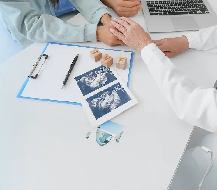 Fertility specialist consulting with a couple reviewing ultrasound scan images and IVF letter blocks